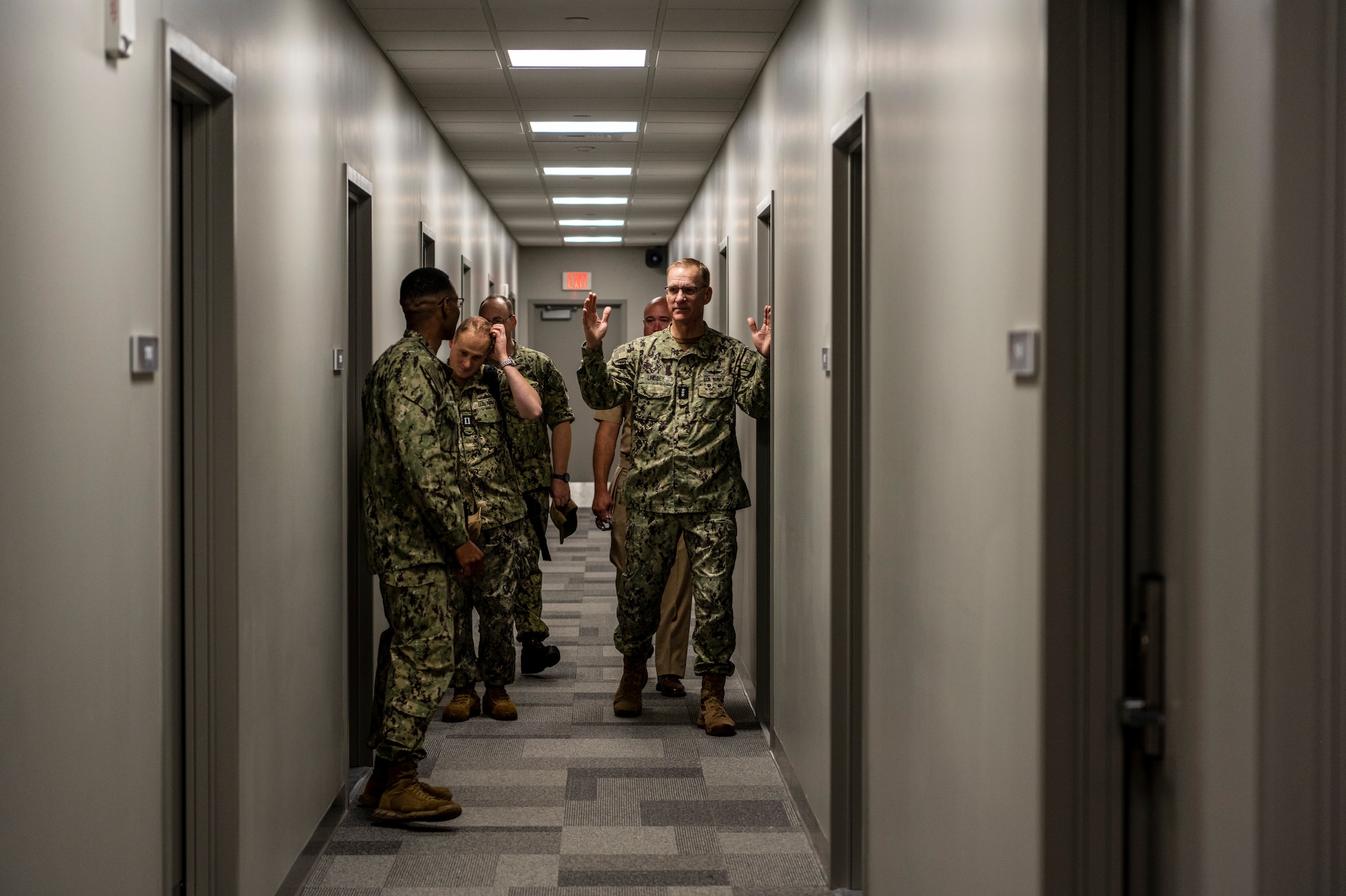 Navy personnel talk down a hallway together.