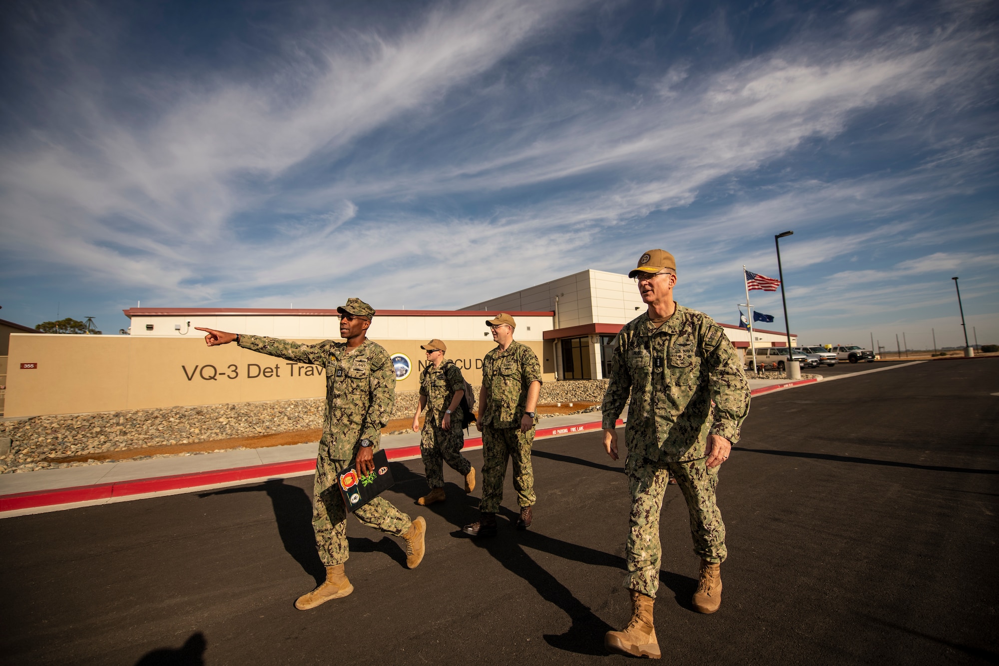 Navy personnel walk outside in a small group.