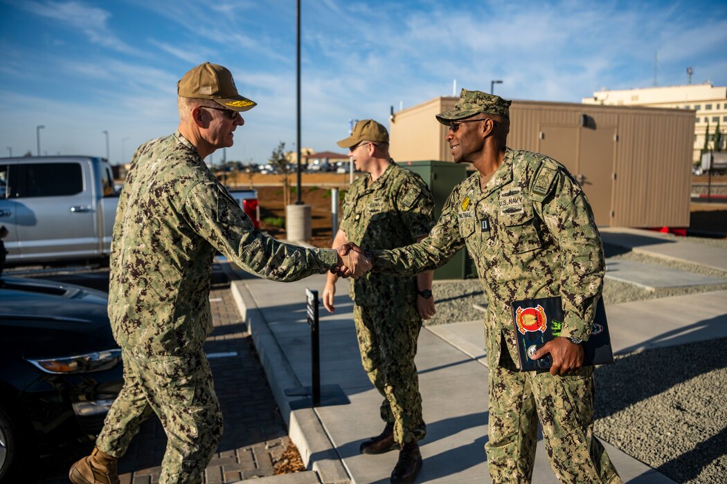 Navy personnel shake hands outside of an entry control point.