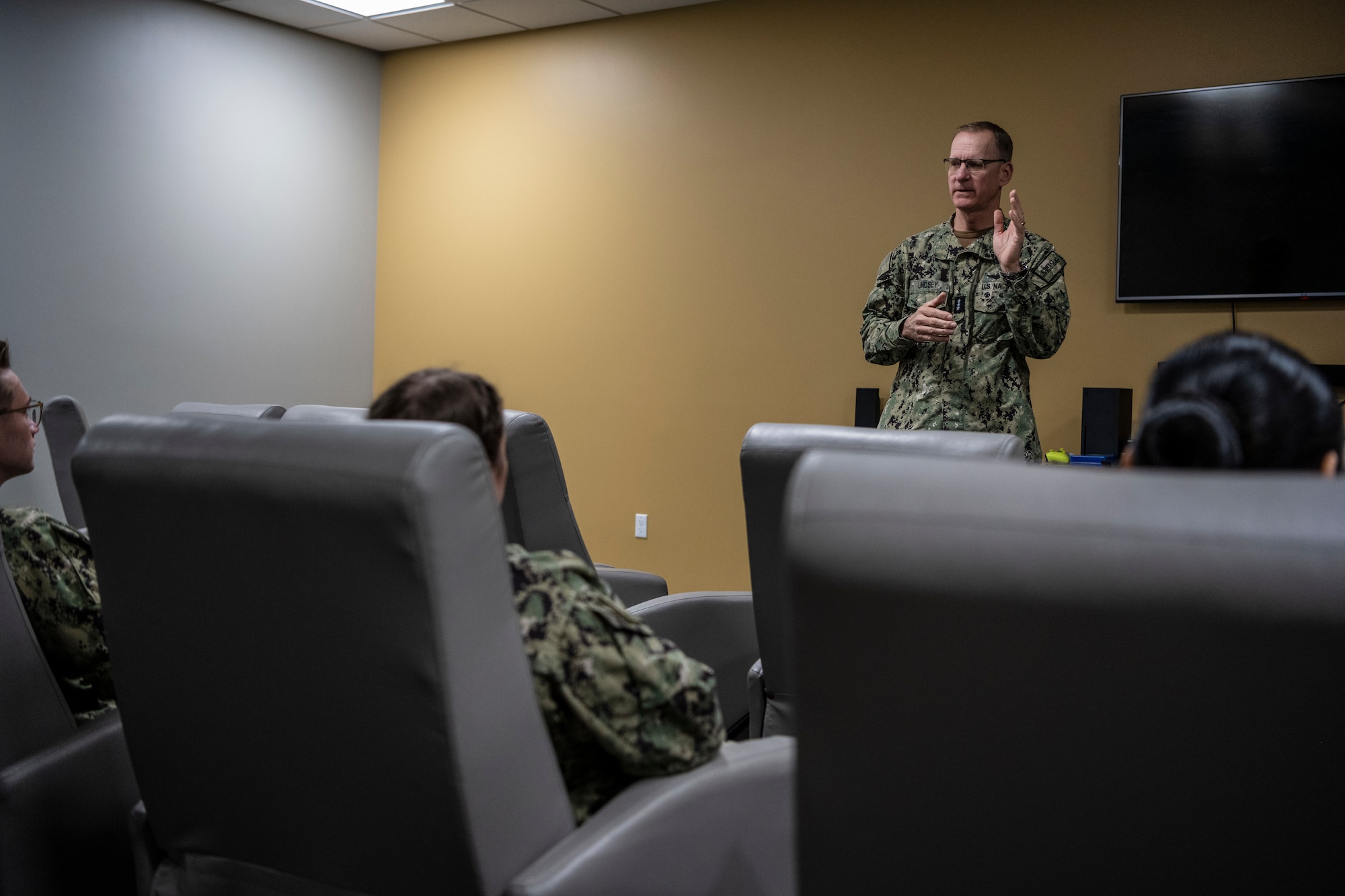 Navy personnel discuss facility security in a room.