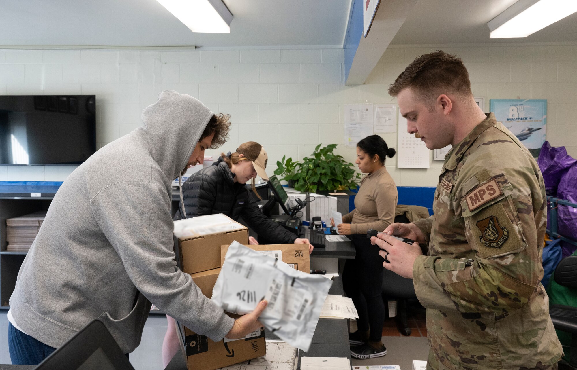 Staff Sgt. Devin Dunlap, 8th Force Support Squadron registered mail NCO in charge, gives packages to a customer at Kunsan Air Base, Republic of Korea, Nov. 26, 2022. The post office receives such an increase of parcels going in and out during the holidays, they open volunteer opportunities to personnel who would like to help maintain a flow of package organization and delivery. (U.S. Air Force photo by Staff Sgt. Sadie Colbert)
