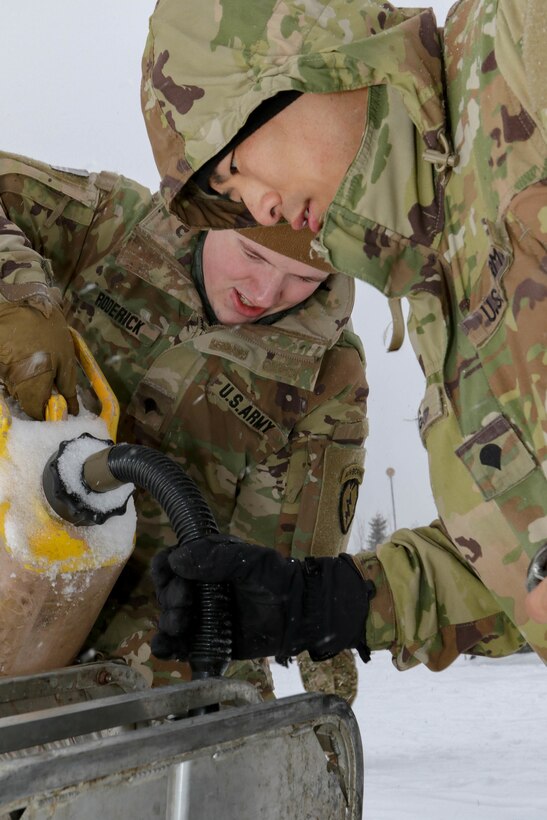 Spc. Cole Roderick and Spc. Jimmy Zhang, Soldiers with 4th Brigade Combat Team, 25th Infantry Division, US Army Alaska load fuel into a heating element used for cleaning dishes after hot meals are served at the Intermediate Staging Base near Fort Greely, AK March 10, 2022. Joint Pacific Multinational Readiness Center 22-02, executed in Alaska with its Arctic environment, builds Soldiers and leaders into a team of skilled, tough, alert, and adaptive warriors capable of fighting and winning anywhere. (Photo by Staff Sgt. Christopher B. Dennis/USARAK PAO NCO)