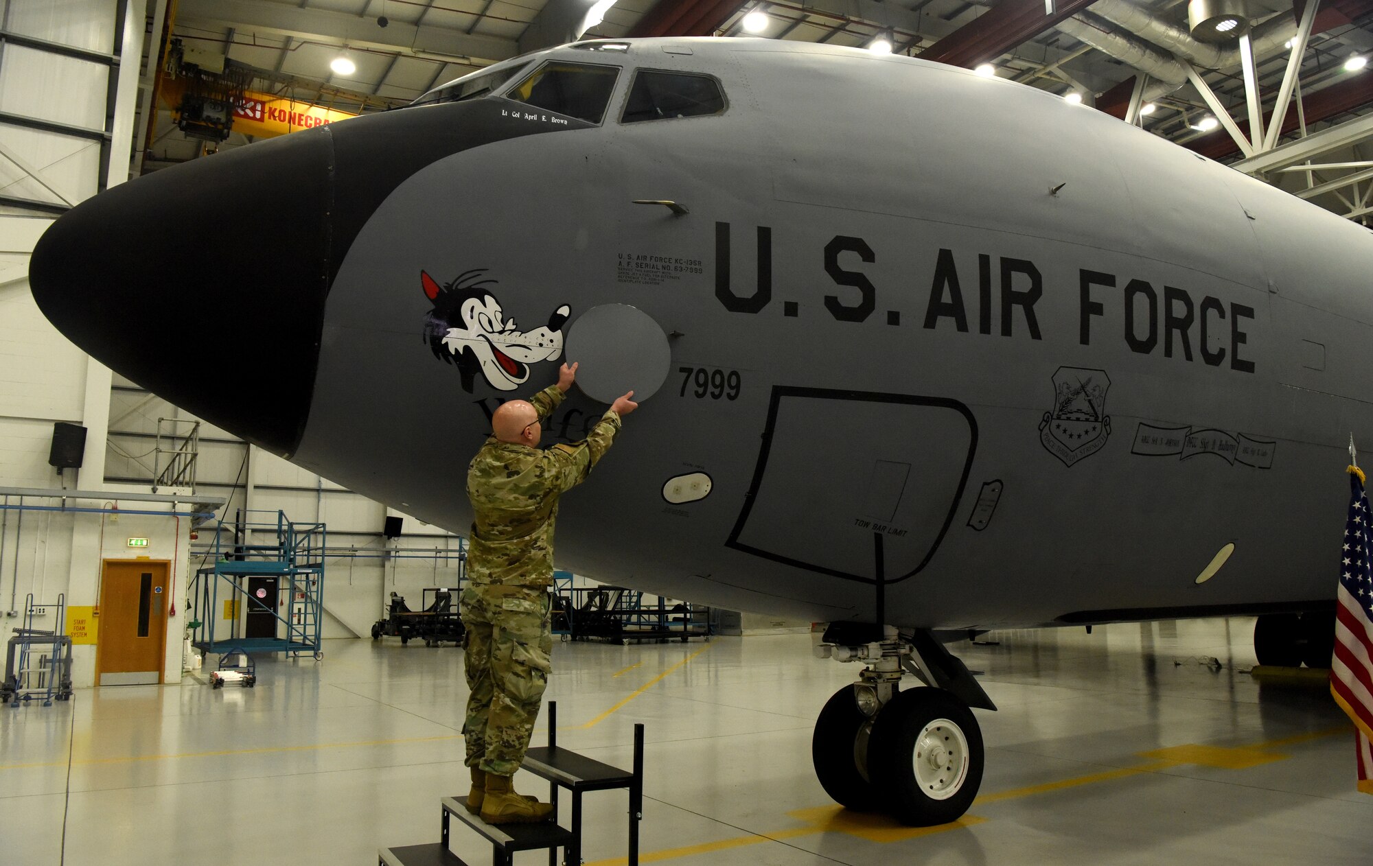 U.S. Air Force Master Sgt. Jeffrey Gehrke, 100th Aircraft Maintenance Squadron production superintendent, removes the cover of aircraft 7999’s “retirement pin” during its retirement ceremony Nov. 23, 2022, at Royal Air Force Mildenhall, England. This was the first official retirement of a KC-135 at RAF Mildenhall. The 59-year-old tanker, which bears the World War II legacy nose art “Wolff Pack,” has taken its last flight and is now at its final resting place in “The Bone Yard” at Davis-Monthan Air Force Base, Arizona, but the legacy “Wolff Pack” nose art will remain at RAF Mildenhall and be transferred to another aircraft. (U.S. Air Force photo by Karen Abeyasekere)