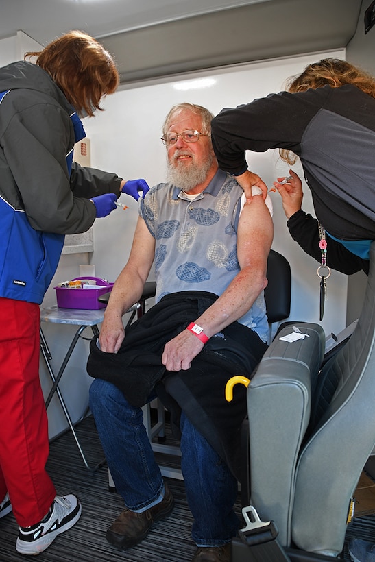 A man gets innoculations in both arms by nurses.