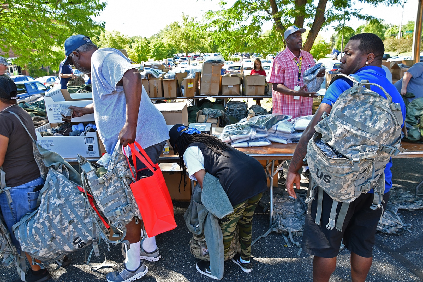 People stand in line for surplus gear at an outdoor table.