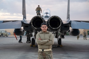 Senior Airman Hector J. Gomez, Jr., Fuels Distribution, 332d Expeditionary Logistics Readiness Squadron Fuels Management Flight, poses behind an F-15E Strike Eagle fighter jet as part of the “Maintainer for a Day” program at an undisclosed location, Nov. 10, 2022. Maintainer for a Day is an initiative that pairs Airmen across the a variety of career fields with members of aircraft maintenance shops for a hands-on learning experience with F-15E Strike Eagle fighter jets. (U.S. Air Force photo by Tech. Sgt. Richard Mekkri)