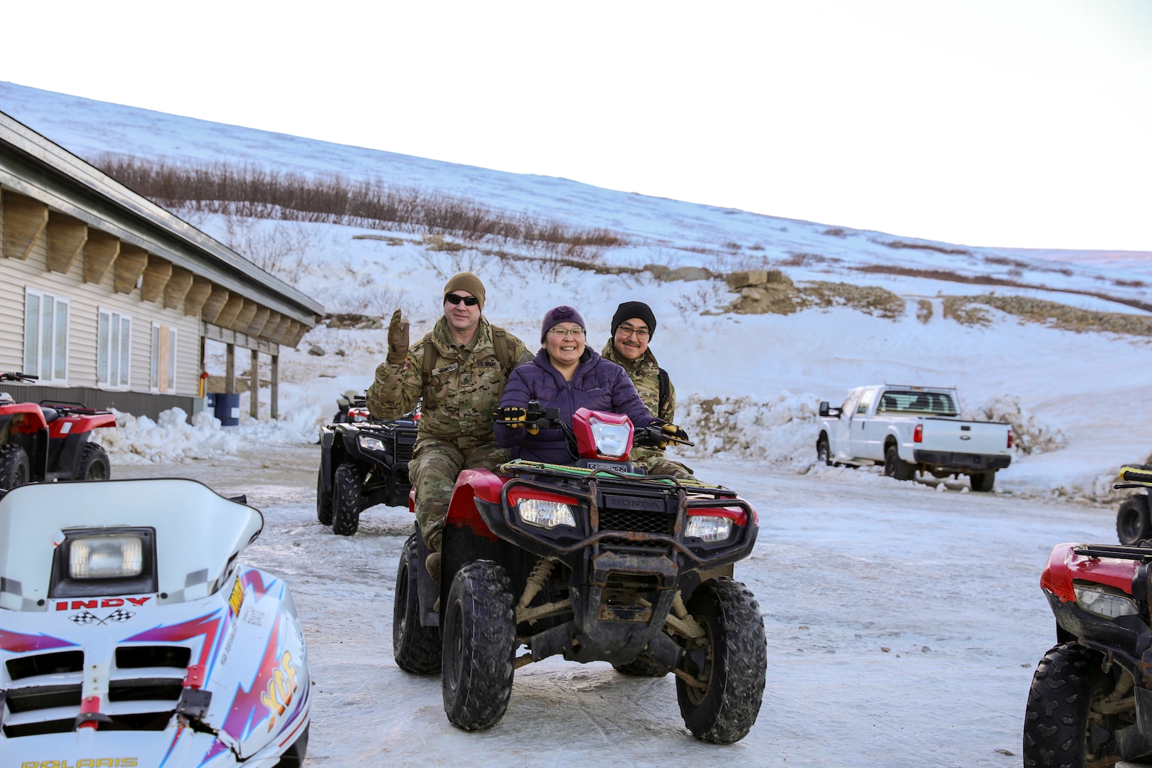 Alaska Army National Guard Staff Sgt. Eddie Jones, left, a recruiter assigned to Bethel with the Recruiting and Retention Battalion, and Pfc. Jared Alirkar, a transportation management coordinator with the 49th Personnel Detachment (Theater Gateway), catch a ride on the back of a four-wheeler during Operation Santa Claus in Scammon Bay Nov. 16, 2022. Operation Santa Claus is the Alaska National Guard’s yearly community relations and support program that provides gifts to children in remote communities across the state.