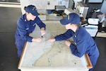 Underway Officer Ensign Katharine Braynard (right) works with Junior Oficer of the Deck, Petty Officer First Class Erin Hunter, with the plan for mooring in Milwaukee to offload buoys, Nov. 27, 2012. Braynard and Hunter were part of an all-female watch executed on the Mackinaw during the ship's transit to Chicago to offload 1,300 Christmas trees as part of this year's Chicago's Christmas Ship event. U.S. Coast Guard photo by Seaman Robert Butler.