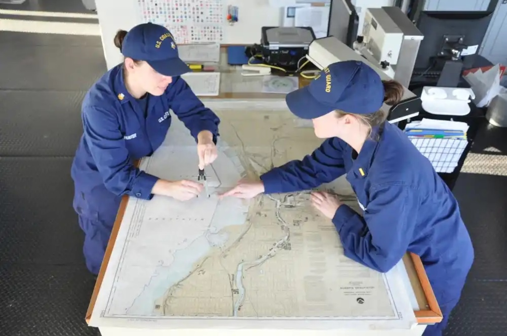 Underway Officer Ensign Katharine Braynard (right) works with Junior Oficer of the Deck, Petty Officer First Class Erin Hunter, with the plan for mooring in Milwaukee to offload buoys, Nov. 27, 2012. Braynard and Hunter were part of an all-female watch executed on the Mackinaw during the ship's transit to Chicago to offload 1,300 Christmas trees as part of this year's Chicago's Christmas Ship event. U.S. Coast Guard photo by Seaman Robert Butler.