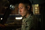 An Airman crosses his arms and smiles in a warehouse