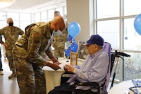 New York Air National Guard Command Chief Master Sgt. Denny Richardson presents a challenge coin to World War II veteran William H. Meyer during his 100th birthday celebration at Shaker Place Nursing Home in Latham, New York, Nov. 28, 2022.