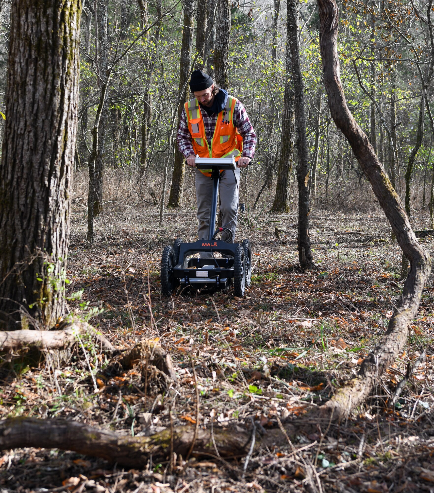 Jacob Jepsen, an archaeologist who specializes in geophysics, operates a ground penetrating radar machine in Rutherford-Shipley Cemetery at Arnold Air Force Base, Tennessee, Nov. 10, 2022. The GPR data gives archaeologists information about what has occurred below the surface to help detect possible grave locations. (U.S. Air Force photo by Jill Pickett) (This image has been altered by obscuring a badge for security purposes.)