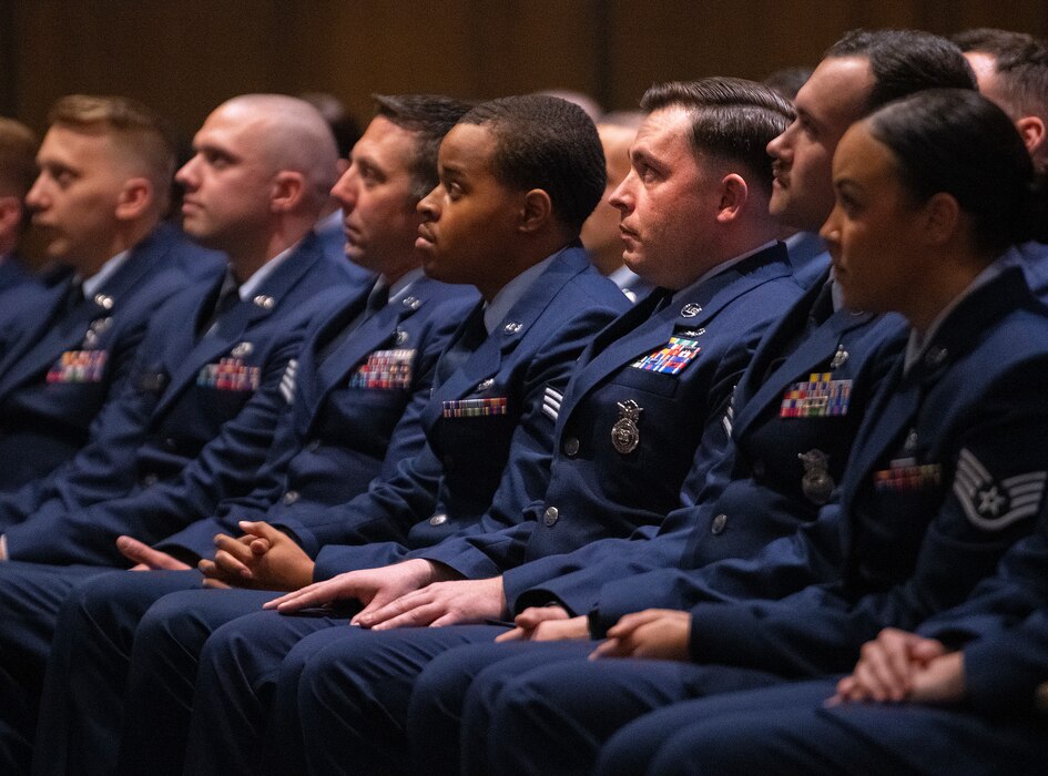A row of Airmen in theater seats with their hands in their laps.