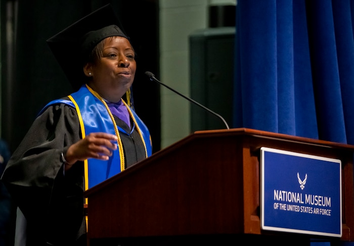 African-American woman at podium in academic robes.