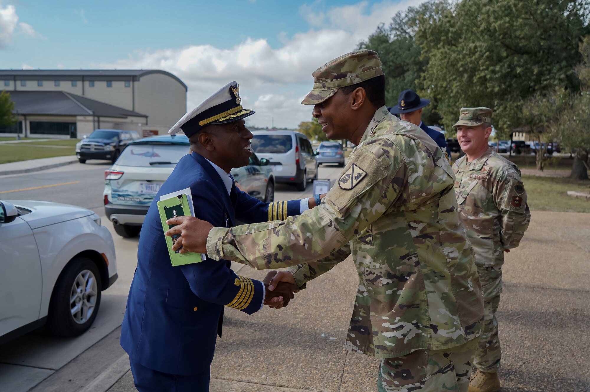 Two men smiling while shaking each other's hand. They are facing each other.