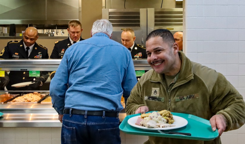 Alaska Army National Guard Staff Sgt. Bernando Rodriguez, 49th Missile Defense Battalion, front, serves up dinner during a Thanksgiving dinner at the Ballistic Bistro on Fort Greely, Alaska, Nov. 23, 2022. Senior leaders of the 49th Missile Defense Battalion and 38th Troop Command served Thanksgiving dinner to Soldiers in a time-honored tradition of demonstrating gratitude and fostering comradery throughout the U.S. Army's ranks. (U.S Army National Guard Courtesy photo)