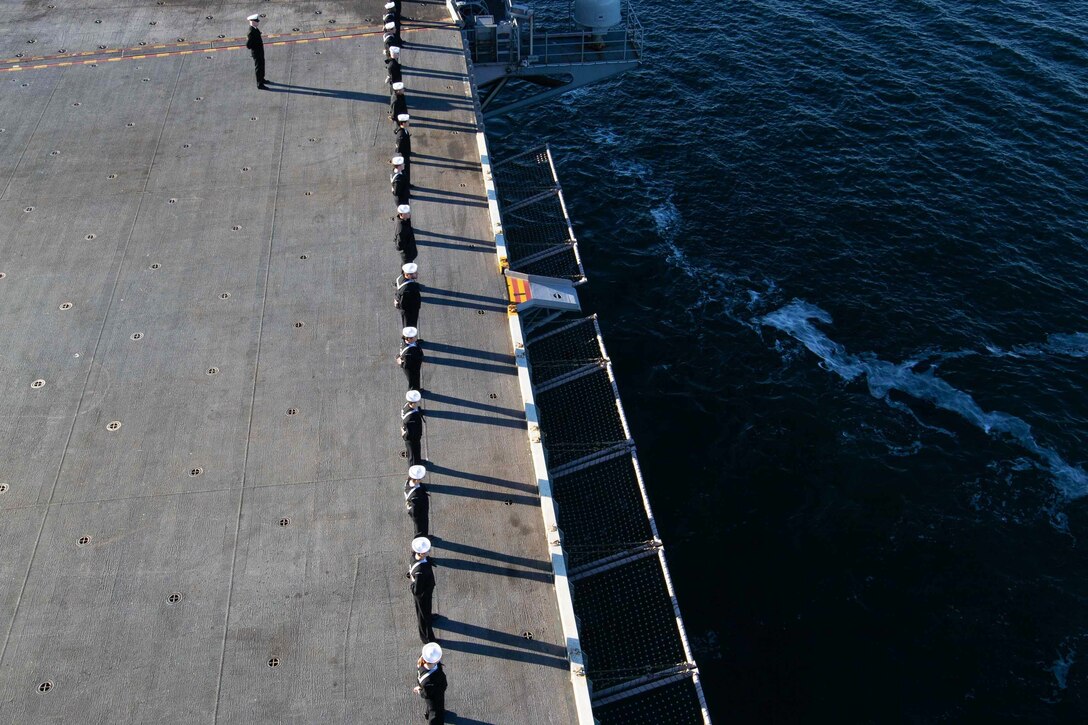 Sailors line the deck of a ship.