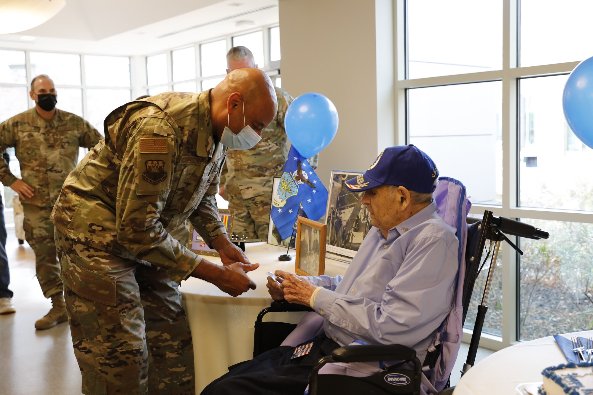 New York Air National Guard Command Chief Master Sgt. Denny Richardson presents a challenge coin to World War II veteran William H. Meyer during his 100th birthday celebration at Shaker Place Nursing Home in Latham, New York, Nov. 28, 2022.