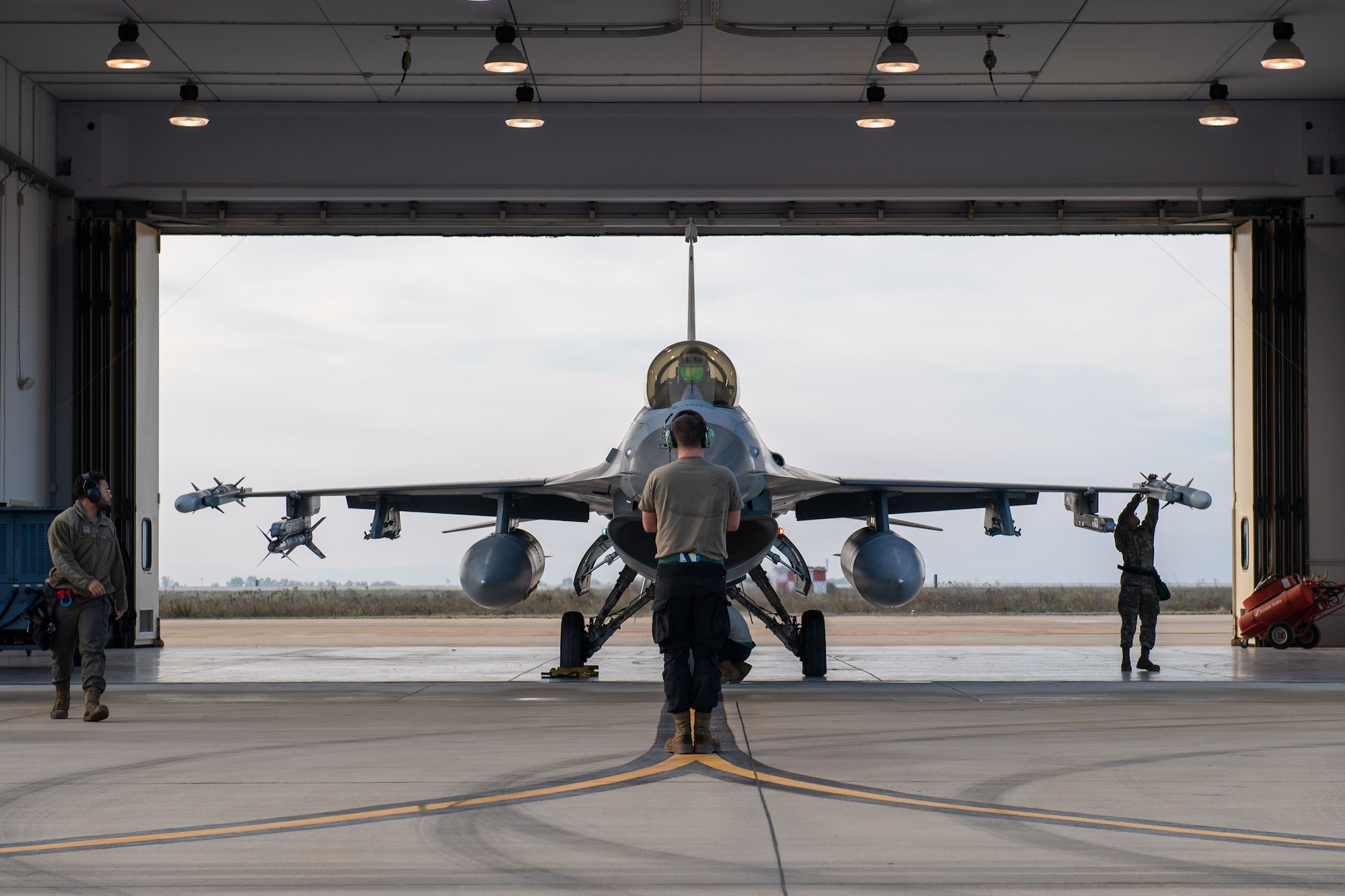 Airman 1st Class Logan Turner, 555th Fighter Generation Squadron crew chief, marshals a U.S. Air Force F-16 Fighting Falcon from the 555th Fighter Squadron out of its hangar during exercise Falcon Strike 2022