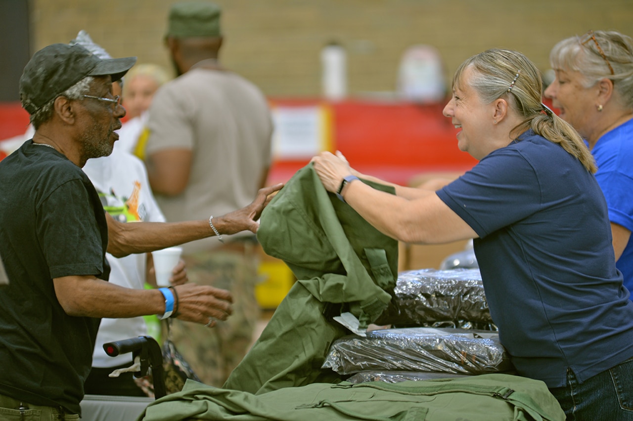 A volunteer hands out duffel bags.