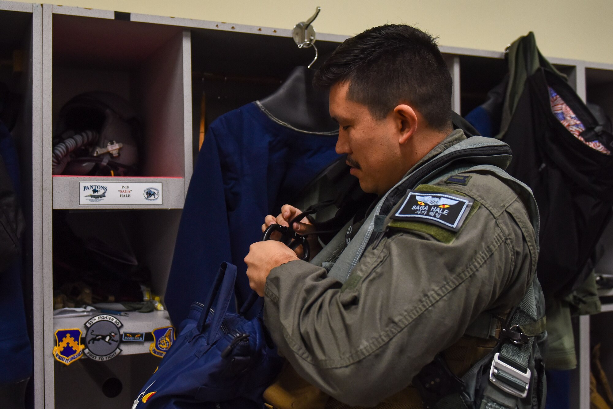 U.S. Air Force Capt. Matthew Hale, 35th Fighter Squadron pilot, dons his aircrew flight equipment at Kunsan Air Base, Republic of Korea, Nov. 30, 2022. Hale grew up on a Navajo Nation reservation in Arizona prior to commissioning into the USAF. (U.S. Air Force photo by Tech Sgt. Timothy Dischinat)