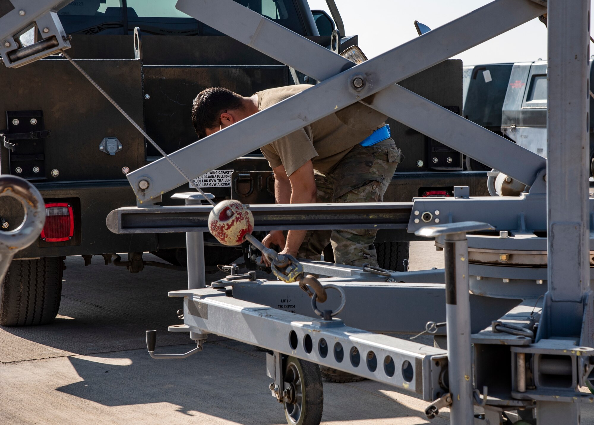 Senior Airman Jacob Karn, an Aerospace Ground Equipment Mechanic with the 332d Expeditionary Maintenance Squadron, connects a canopy crane to a trailer hitch at an undisclosed location, Southwest Asia, Nov. 11, 2022.  These cranes are used to remove the canopy of an F-15E Fighting Falcon for repairs. (U.S. Air Force photo by: Tech. Sgt. Jim Bentley)