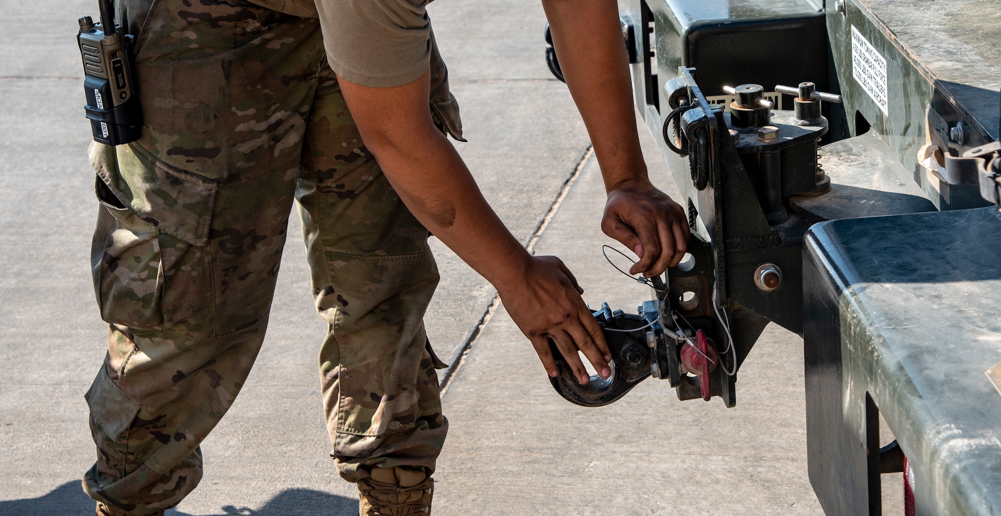 Senior Airman Jacob Karn, an Aerospace Ground Equipment Mechanic with the 332d Expeditionary Maintenance Squadron, puts a pin in a truck's tow hitch at an undisclosed location, Southwest Asia, Nov. 11, 2022. These cranes are used to remove the canopy of an F-15E Fighting Falcon for repairs. (U.S. Air Force photo by: Tech. Sgt. Jim Bentley)