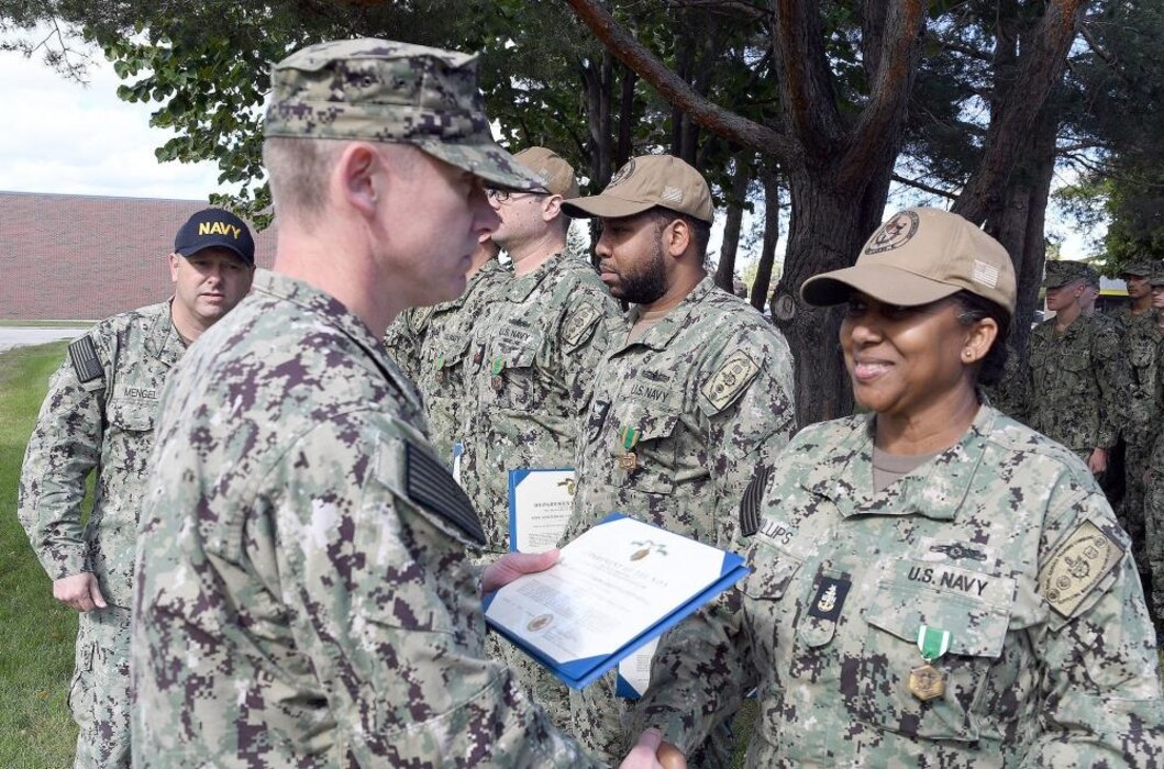 GREAT LAKES, Ill. (September 27, 2022) – Capt. Frank Brown, deputy commander of operations, Naval Service Training Command (NSTC), presents Senior Chief Boatswain’s Mate Fredrika Phillips with an end of tour Navy and Marine Corps Commendation Medal outside the USS North Caroline Transient Barracks on Naval Station Great Lakes here, Sept. 27. The medals were presented to several reserve Sailors who were completing their annual active duty time leading, mentoring and taking care of transient Sailors waiting for their next duty assignment orders. (U. S. Navy photo by Scott A. Thornbloom/Released)