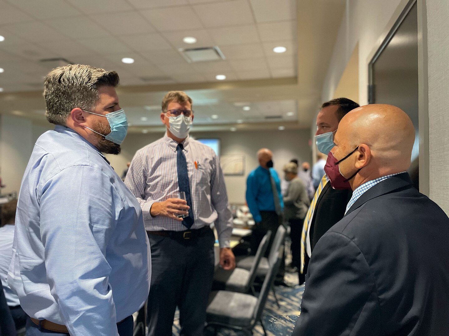 DCMA and Navy personnel have an informal discussion together in a conference room between formal presentations.