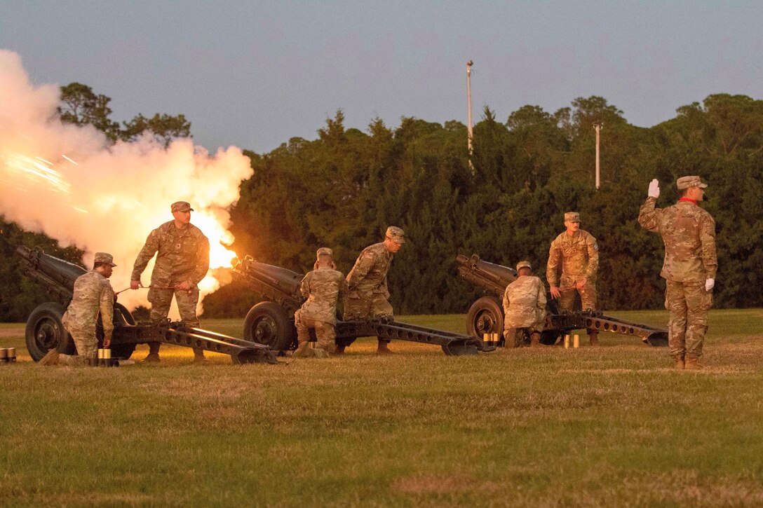 Soldiers fire cannons during a ceremony.