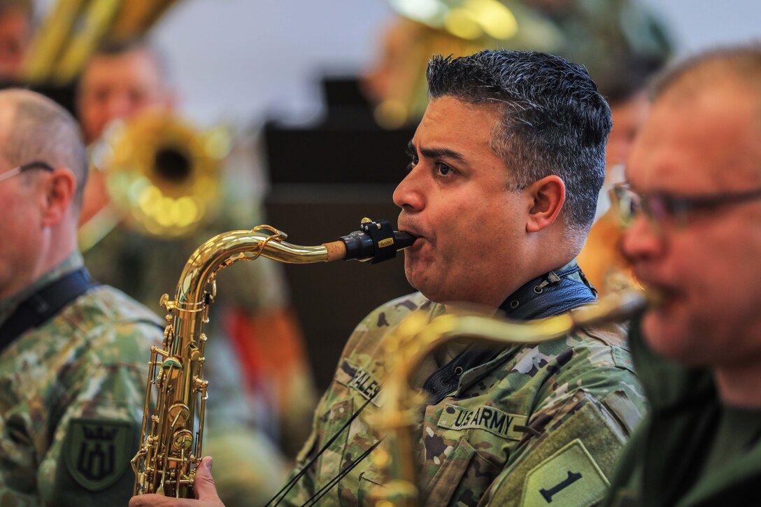 Four soldiers play trumpet, one in focus.