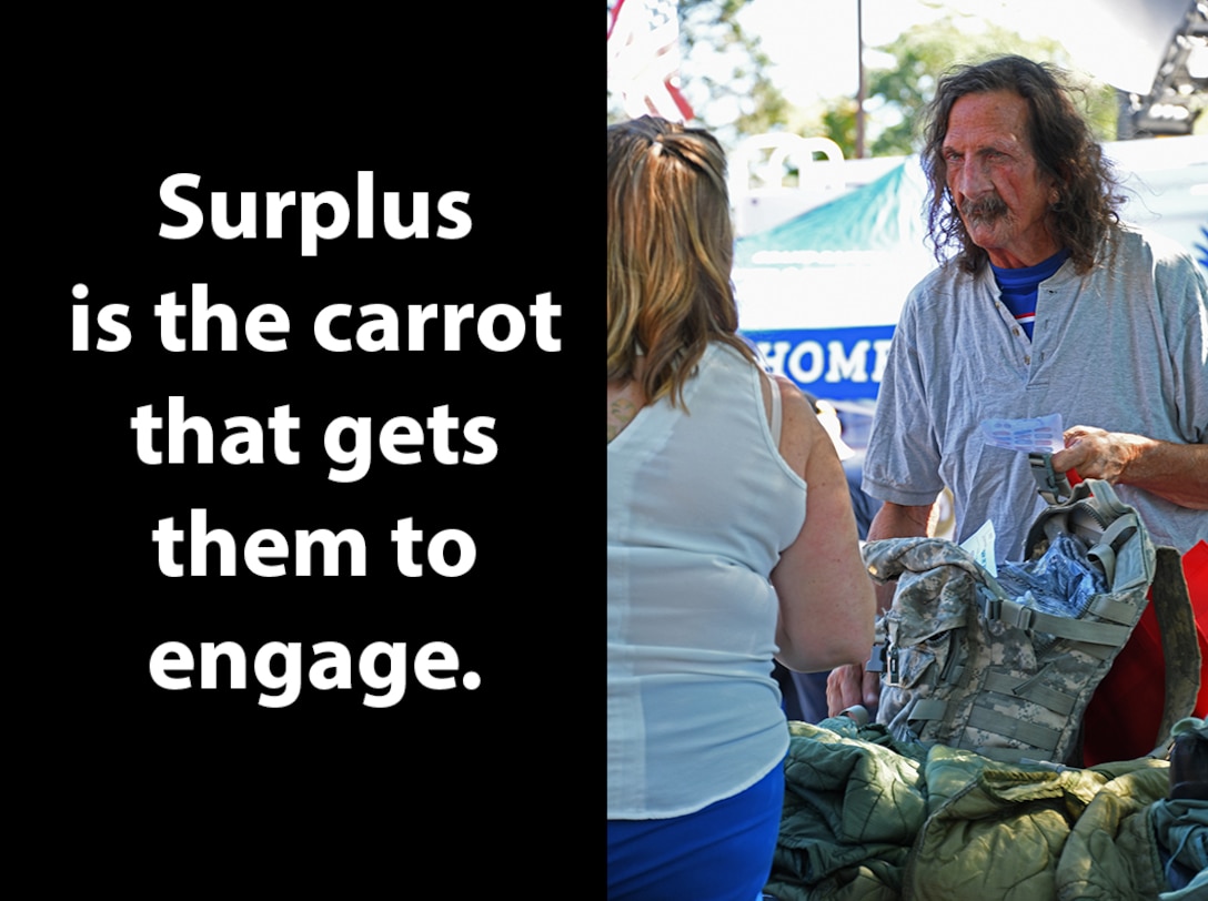 A man is helped with surplus clothing by a stand down event worker.