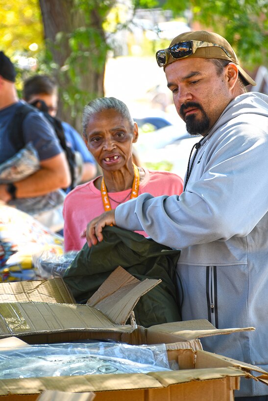 A man helps a woman with surplus clothing.