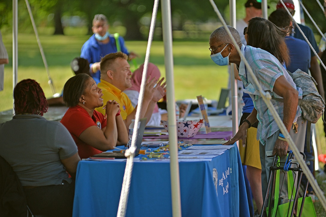 Veterans talk with specialists at outdoor booths.