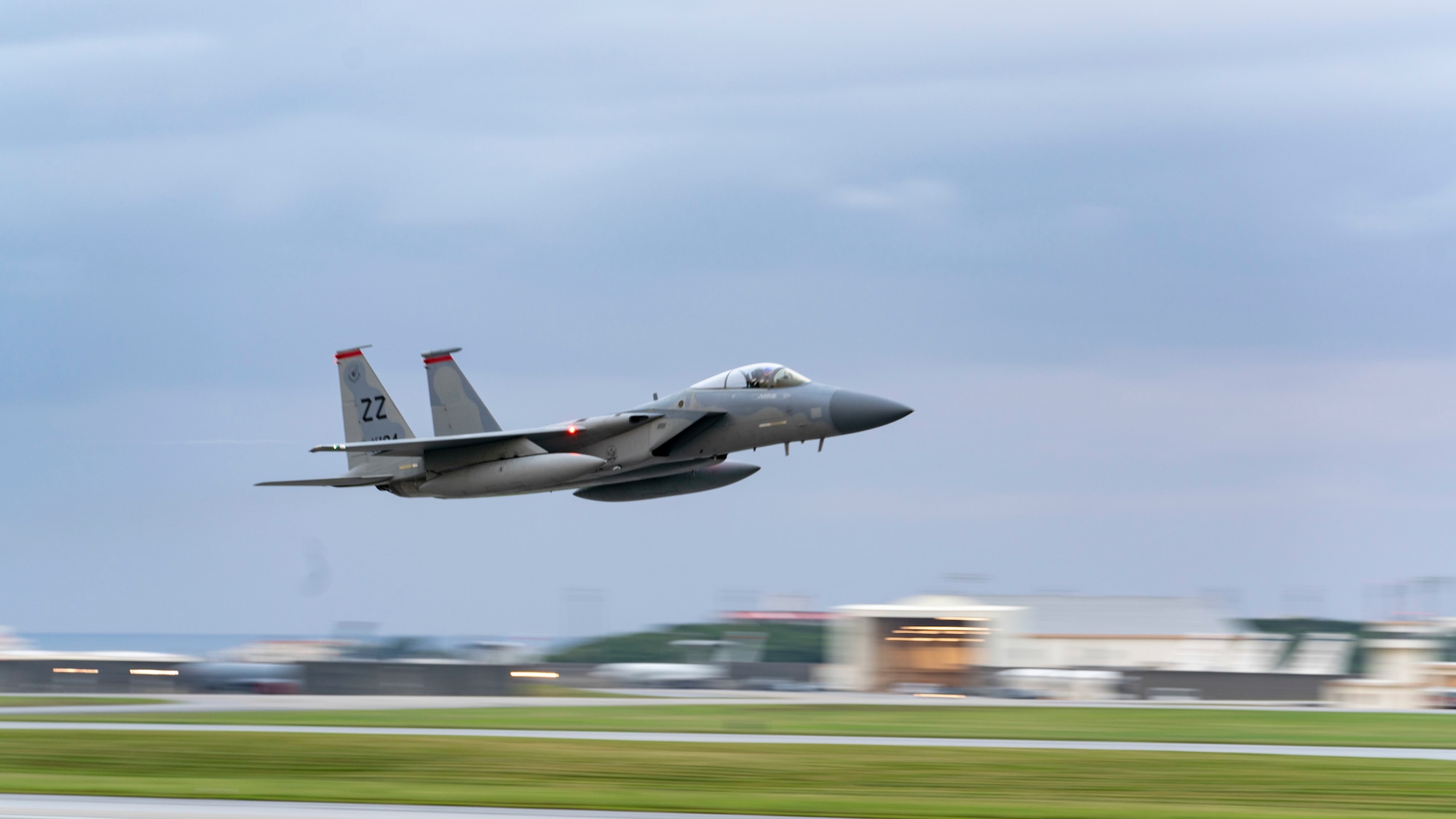 A grey Air Force F-15 takes off over a landing strip at Kadena Air Base