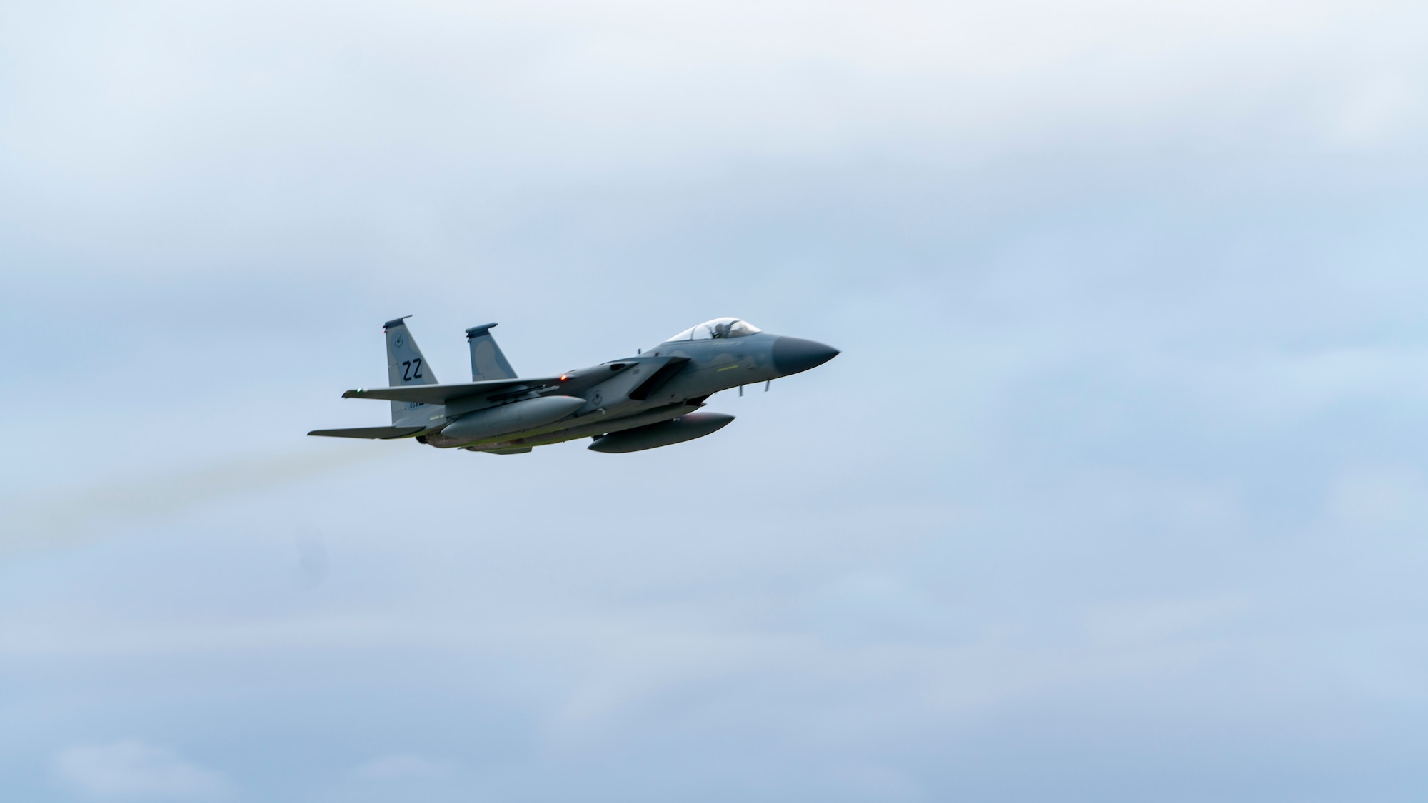A grey Air Force F-15 takes off over a landing strip at Kadena Air Base