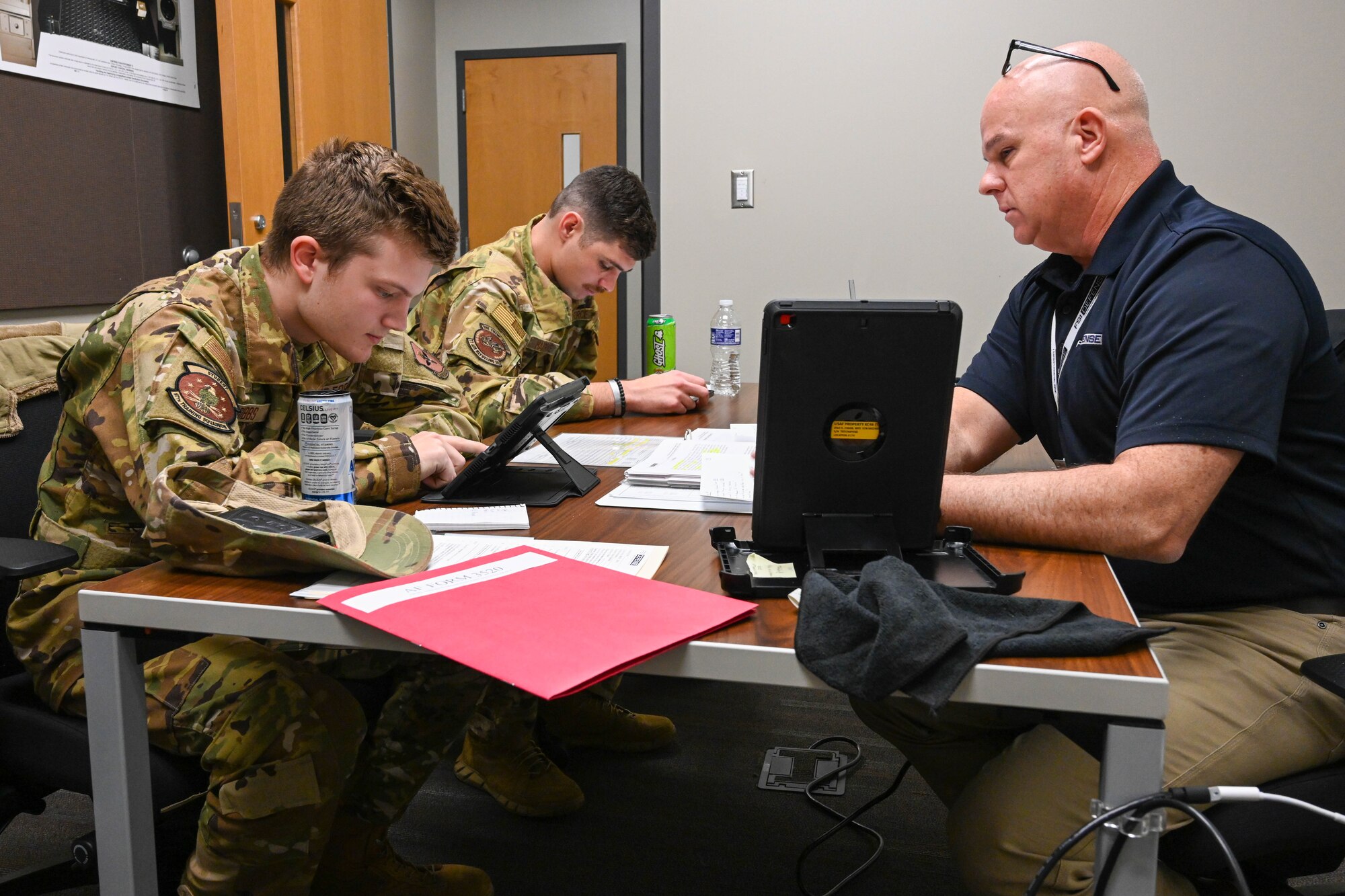 From left, Airman 1st Class Luke Gibbs, 97th Training Squadron (TRS) boom operator student, Staff Sgt. James Hargrove, 97th TRS boom operator student, and Mike Morris, KC-46 Pegasus boom operator instructor, go over a preflight plan before going into a simulator at Altus Air Force Base, Oklahoma, Nov. 29, 2022. Gibbs and Hargrove are both pipeline students, however, Hargrove is cross training from another career field. (U.S. Air Force photo by Senior Airman Trenton Jancze)
