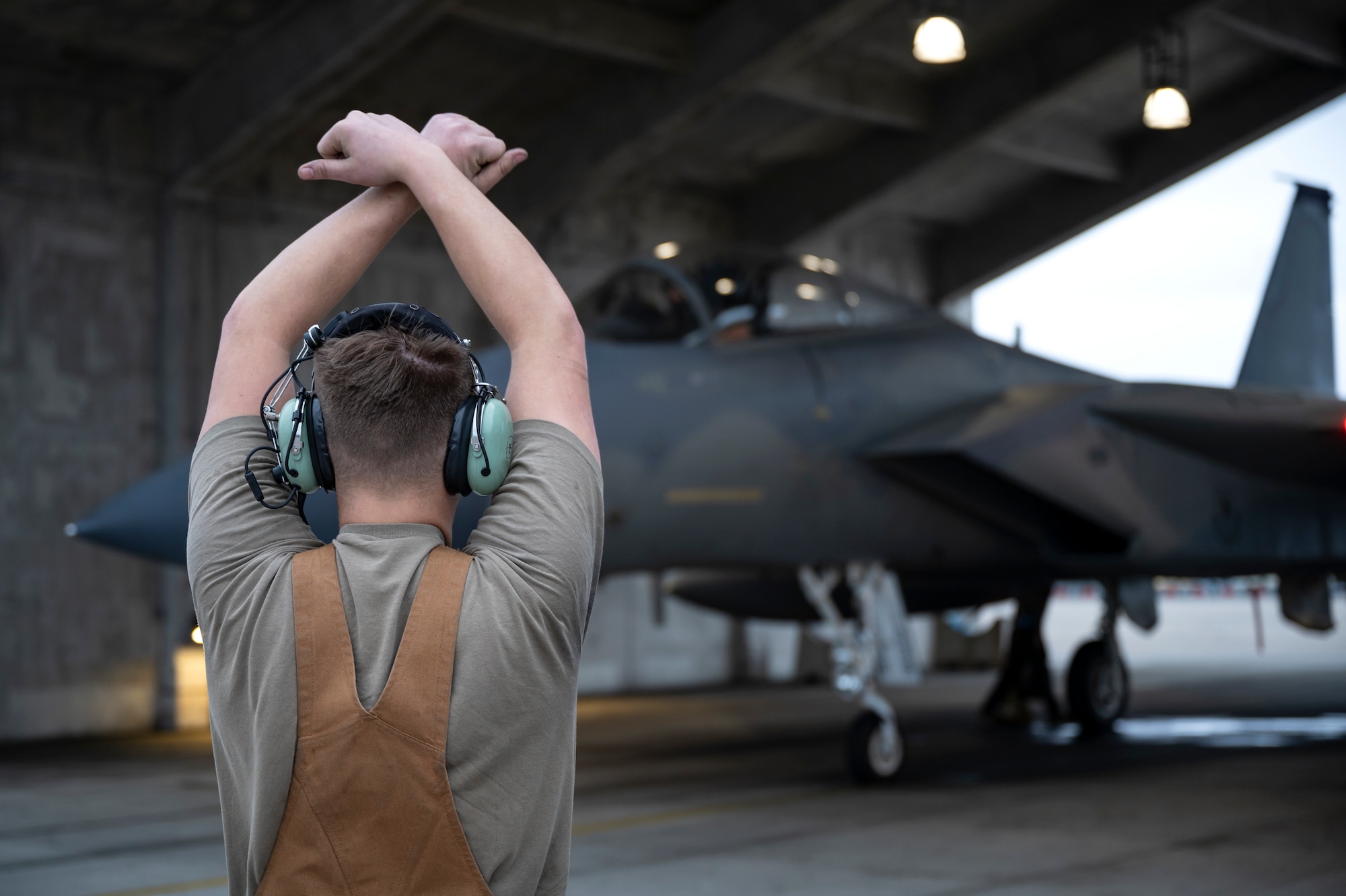 A U.S. Air Force crew chief assigned to the 44th Aircraft Maintenance Unit prepares to marshal an F-15C Eagle onto the taxiway at Kadena Air Base, Japan, Dec. 1, 2022. As a part of its modernization plan, the 18th Wing is retiring its aging fleet of F-15C/D Eagles that have been in service for more than four decades. (U.S. Air Force photo by Senior Airman Jessi Roth)