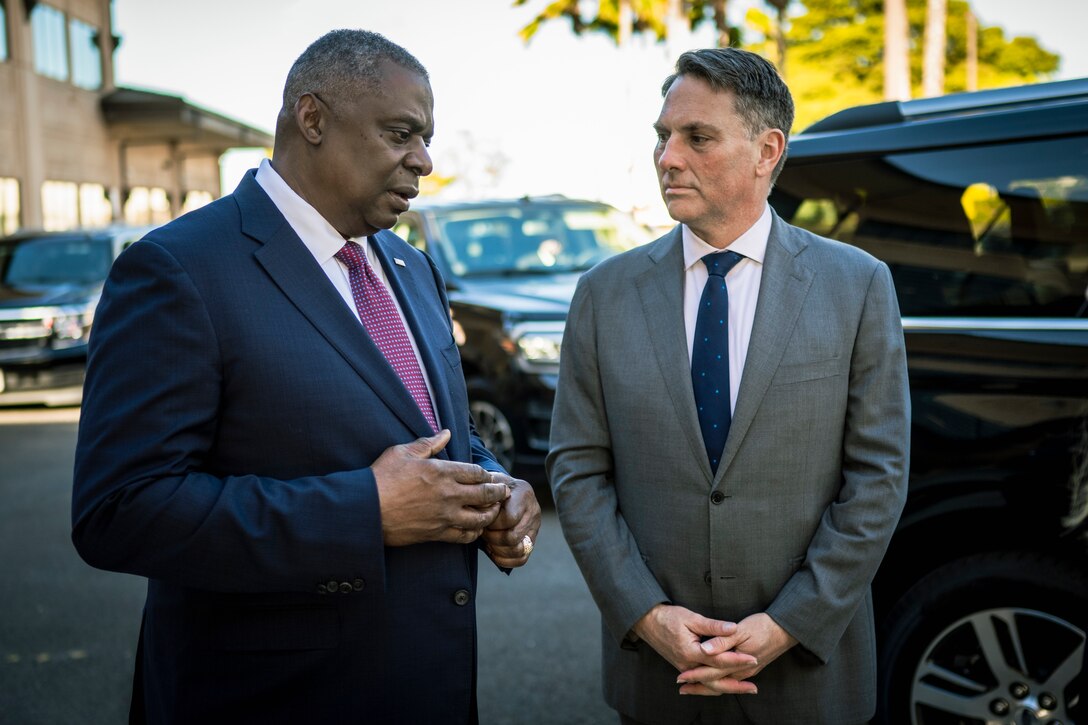 One man listens as another man speaks.