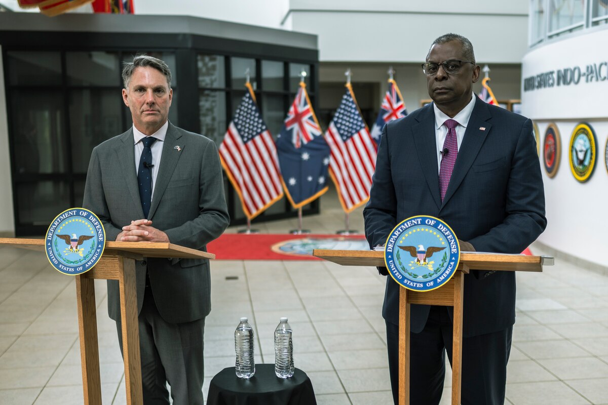 Two men stand at podiums next to each other.