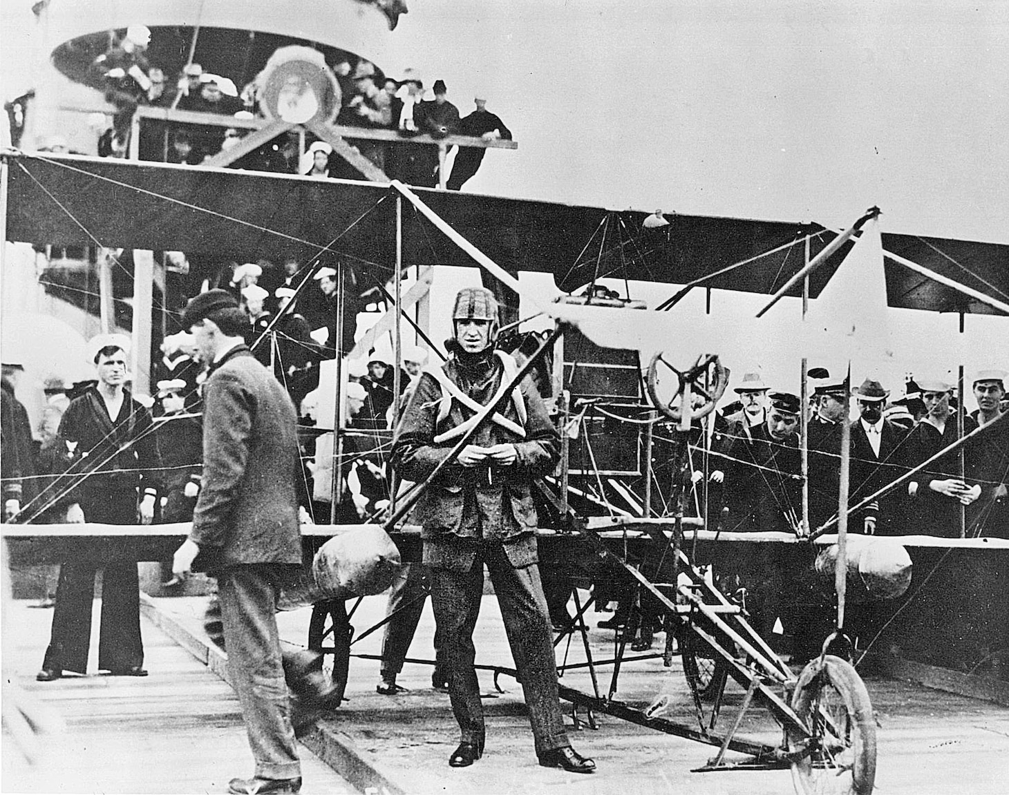 Eugene B. Ely by his Curtiss Model D between landing and takeoff on the armored cruiser USS Pennsylvania (ACR-4/CA-4), January 18, 1911. Note his padded football helmet and improvised personal flotation inner tubes. Note also, the inset photo of a road sign on eastbound Virginia State Highway 60 just outside NAS Norfolk, which I took in 1984. It commemorates Ely’s flight on November 14, 1910, from the cruiser USS Birmingham (CS-2), the first aircraft launch from a ship and his subsequent landing on a nearby beach near Willoughby Spit.