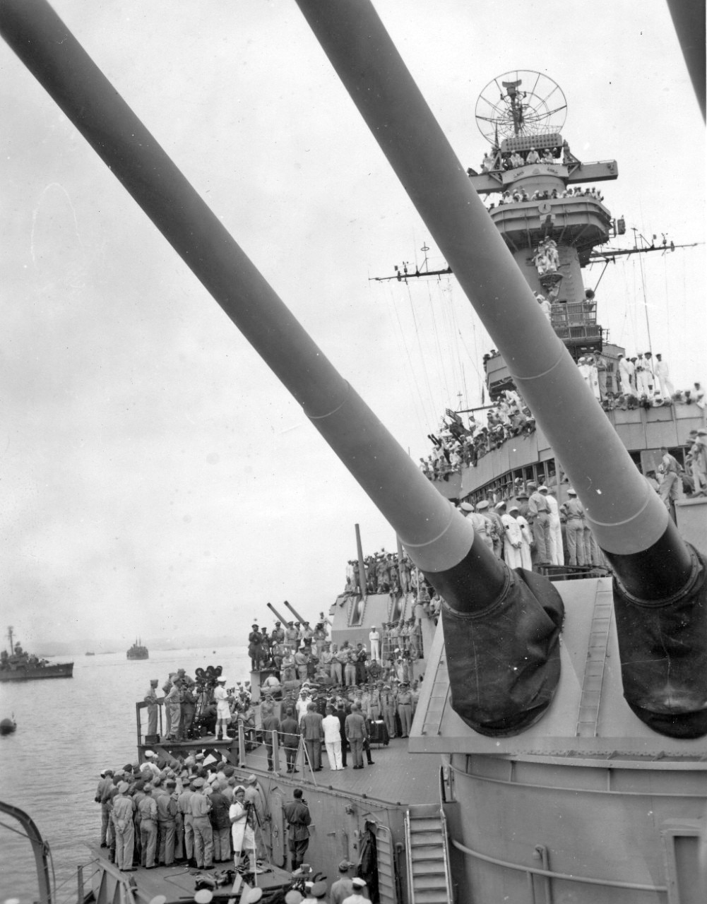 Viewing space was crowded aboard the Missouri on September 2nd. Framed by two of the barrels of three-16-inch guns of one of battleship’s 2 forward turrets (with one rearward –facing turret), servicemen of the US Navy and Marine Corps, as well as members of other nations’ services strain to see and hear the historical event ending World War II.