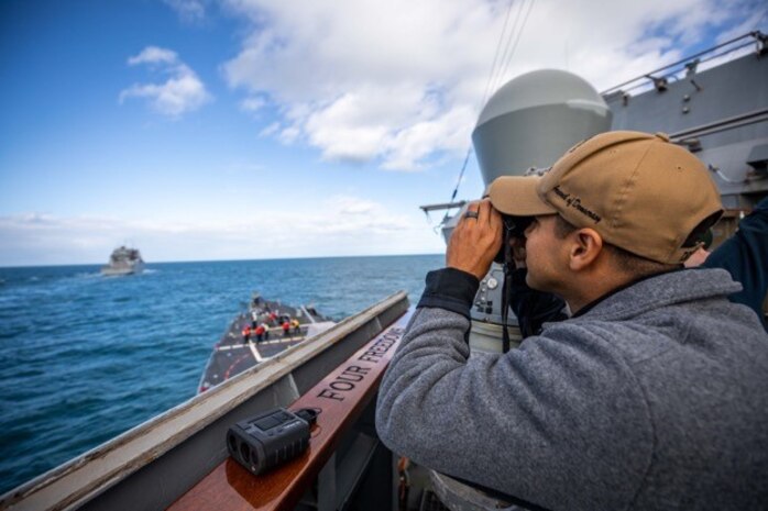 Ensign Ernan Lopez looks through a laser-range finder on the bridgewing of the Arleigh Burke-class guided-missile destroyer USS Roosevelt (DDG 80) as the ship prepares to conduct a replenishment-at-sea with dry cargo ship USNS William McLean (T-AKE 12), Oct. 1, 2022.
