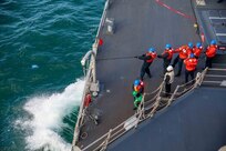 Sailors hold a phone and distance line aboard the Arleigh Burke-class guided-missile destroyer USS Roosevelt (DDG 80) as the ship conducts a replenishment-at-sea with dry cargo ship USNS William McLean (T-AKE 12), Oct. 1, 2022.