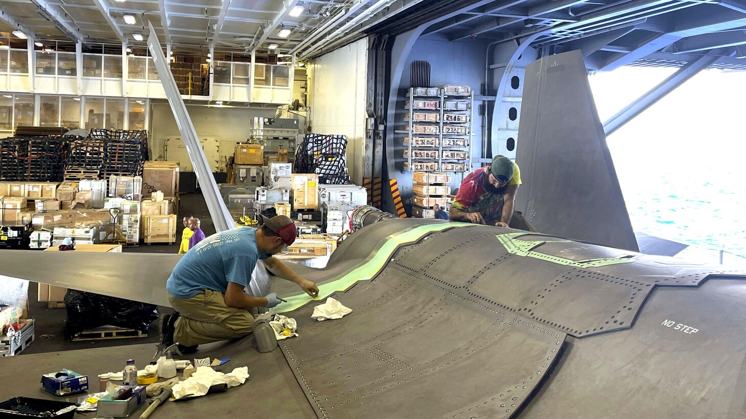 Steven Cope, left, and Joe Shanda, both members of the Fleet Readiness Center East (FRCE) F-35 Rapid Response Team (RRT), perform maintenance on an F-35C for Marine Fighter Attack Squadron 314 (VFMA-314) aboard the USS Abraham Lincoln, underway in the Indo-Pacific region. The FRCE artisans deployed to the aircraft carrier to assist with fixes that were beyond the scope of the organizational-level repairs provided by squadron maintainers.