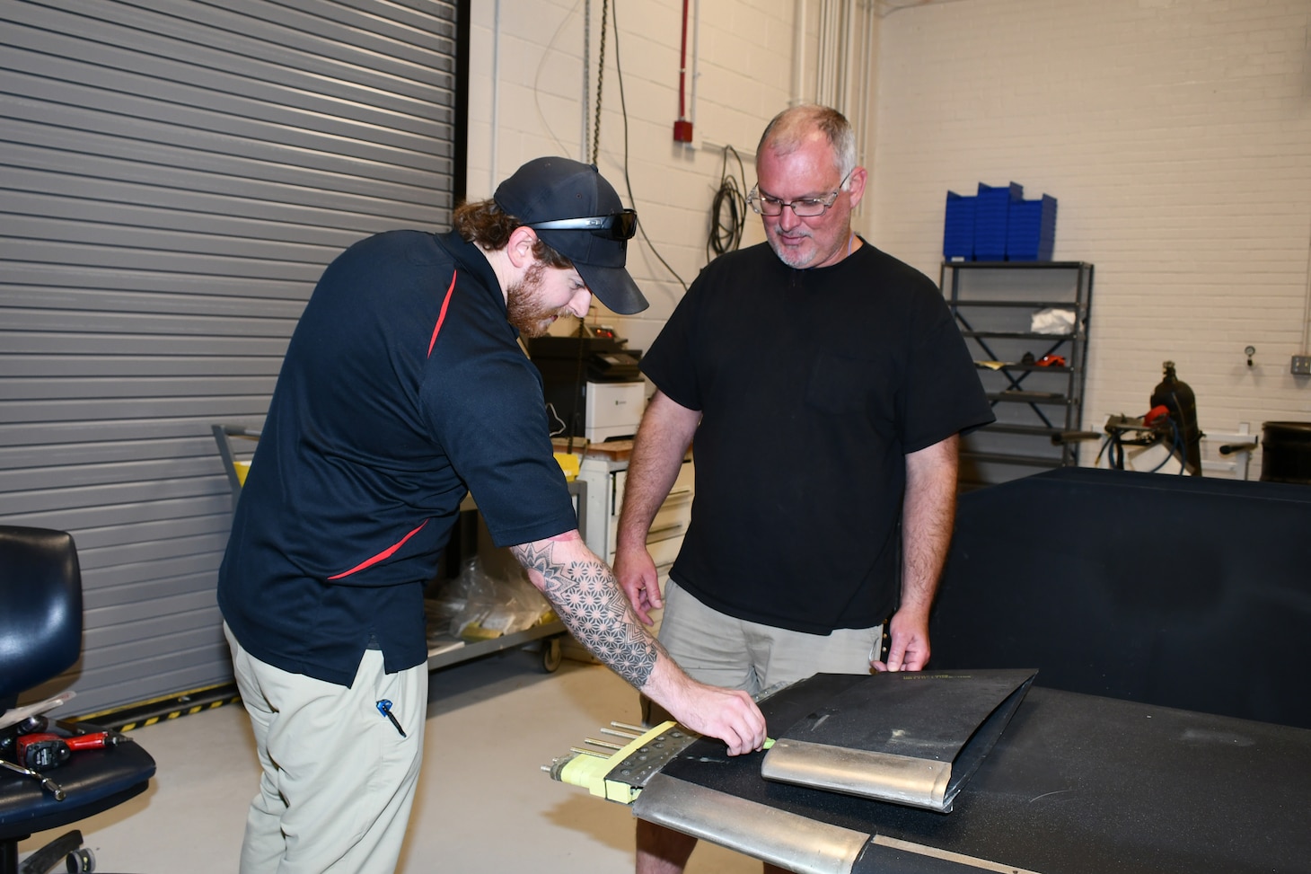 Joshua Peedin, left, senior rotor systems engineer for the H-53 Fleet Support Team, and Robert Call, work leader for the dynamic components shop, inspect the weights used to balance an H-53E rotor blade. Fleet Readiness Center East uses the universal static balance fixture to balance rotor and tail blades for the H-53E, V-22 and H-1 helicopters, and the H-53K program plans to use the fixture to balance its blades as well.