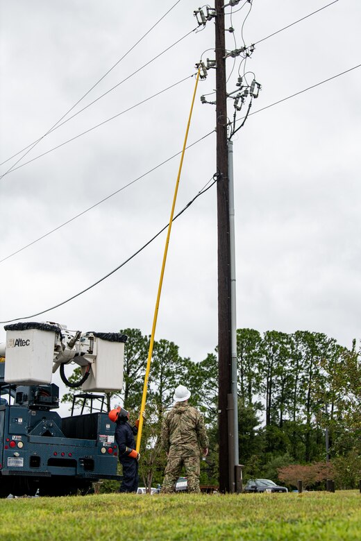 An Airman replaces a fuse on a power line