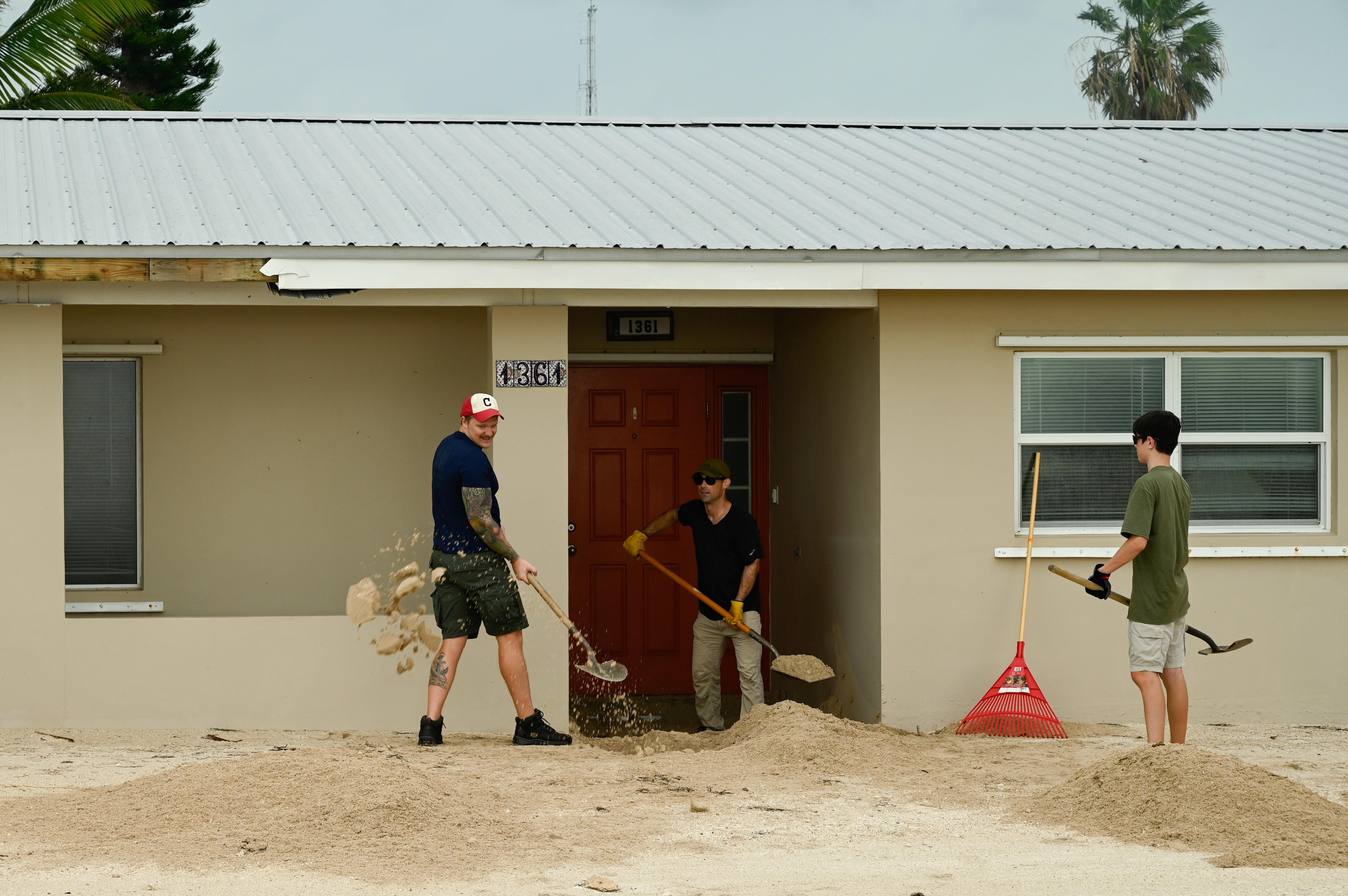 Volunteers clear sand and debris from residential homes at Naval Air Station Key West after Hurricane Ian.