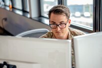 Man in glasses looking at two computer screens