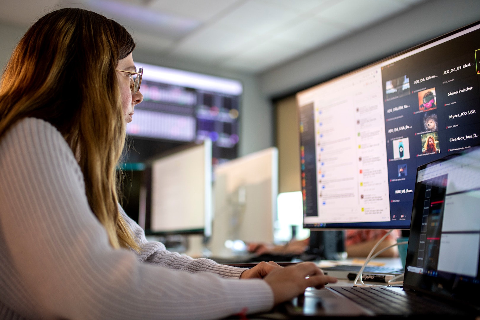 Woman in glasses looking at computer screen and typing